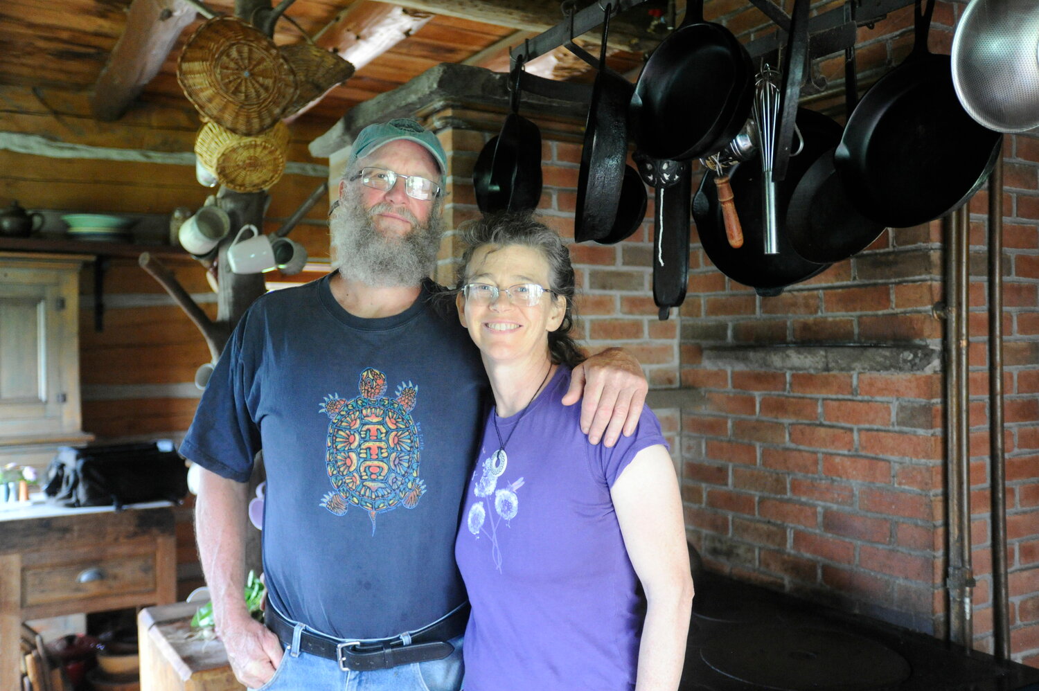 A homesteading couple. Wes and Amy Gillingham pose in their kitchen with the Finnish masonry stove in the background.